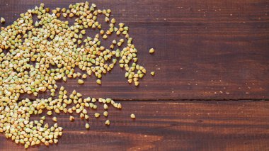 Kahverengi ahşap bir yüzeye kavrulmuş karabuğday ezmesi dökülür. Boşluğu kopyala.