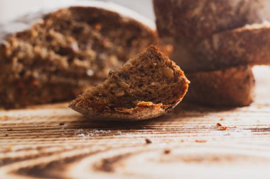 Yuvarlak şekilli, ayçiçeği tohumlu çavdar ekmeği, ahşap bir arka planda havuç dilimleri..