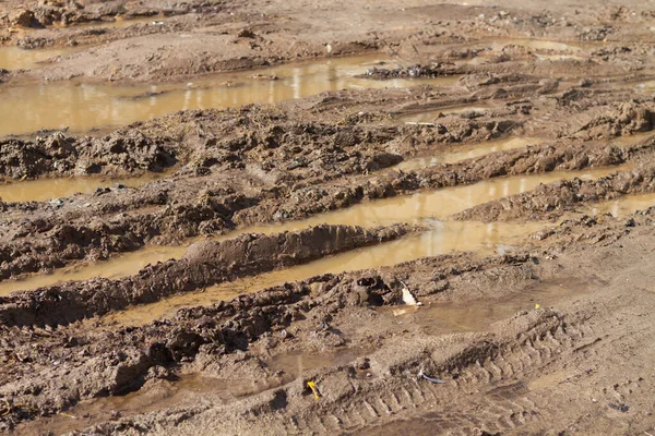 Mud and puddles on the road with traces of car wheels in the spring or autumn on the road.