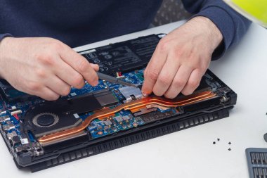 Bir ofis ekipmanı tamircisi bir hata bulmak için bir dizüstü bilgisayarı söker.