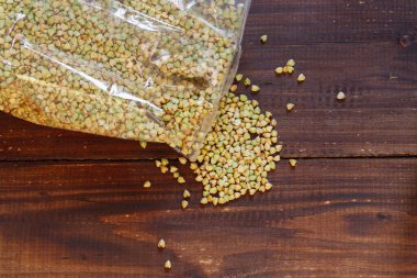 Közlenmemiş yeşil karabuğday kahverengi bir masanın üzerine dökülür.