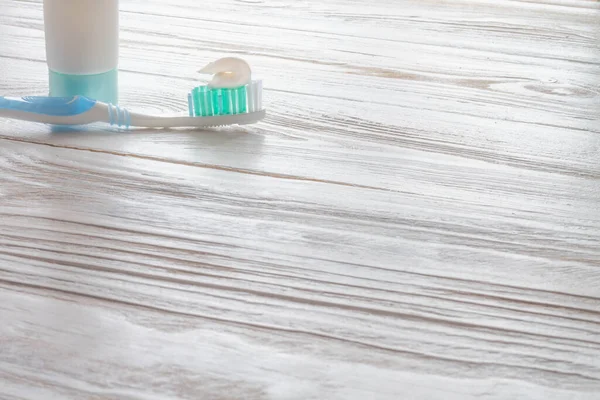 Spazzolini e dentifricio su un tavolo di legno bianco. Accessori per la pulizia dei denti blu — Foto Stock