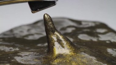 Manyetik plastiksin bir koni şeklinde yayılır ve onu takip eder, bir küp şeklinde metal mıknatısın arkasında eğilir..