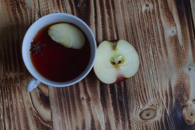 Elma çayı ve bir dilim kırmızı elma eski ahşap bir bej masa üzerinde.