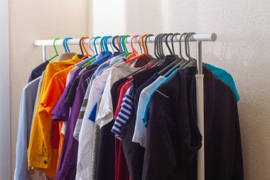 Elbiseler askıda asılı. Parlak giysiler bir askıda saklanıyor..