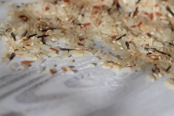 Le riz mélangé est éparpillé sur une table en bois blanc. Du riz cru. Contexte. Espace de copie — Photo