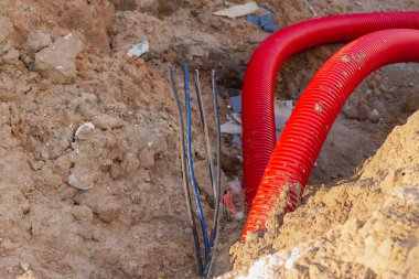 Bir evin inşaatı sırasında yeraltına elektrikli bir kabloyla izole edilmiş plastik bir boru döşemek.
