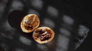 Siyah arka planda kurumuş ceviz çekirdeği olan boş bir ceviz kabuğu..