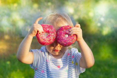 Güzel bir kız bebek. 2 yaşında. Doğada yazın iki pembe çörekle gözlerini kapatıyor..