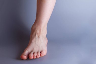 Gri arka planda 7 yaşında bir erkek bebeğin bacağı. Boşluğu kopyala.