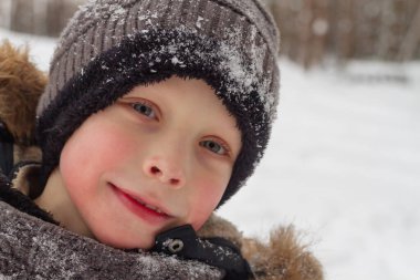 Ormandaki Avrupalı çocuk kışın kar altında şapkasıyla.