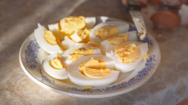 Bir tabakta haşlanmış tavuk yumurtalarını dilimle. Bıçak ve yumurtanın kabuğu..