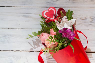 Beyaz arka planda kırmızı karton bir sepet içinde güzel bir buket..