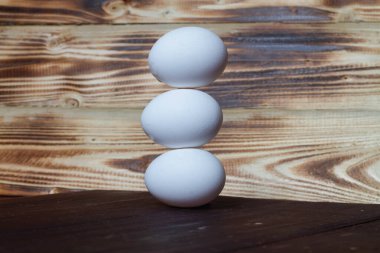 Tahta zemin üzerinde üç beyaz tavuk yumurtası piramidi..