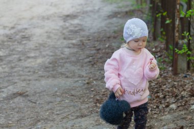 Pembe kabarık ceketli şık bir kız çocuğu kasabada yürür..