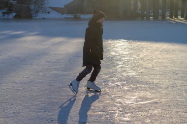 Genç bir çocuk donmuş bir nehrin ya da gölün buzlu sabahında paten kayar..