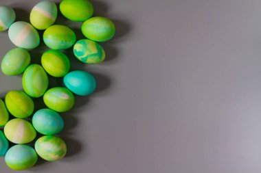 Paskalya arka planında mavi ve yeşil renkli Paskalya yumurtaları gri bir masanın kenarında..