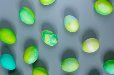 Çiçeklerin doğal tonlarıyla uyum içinde yeşil ve mavi yumurtaların Paskalya arkaplanı.