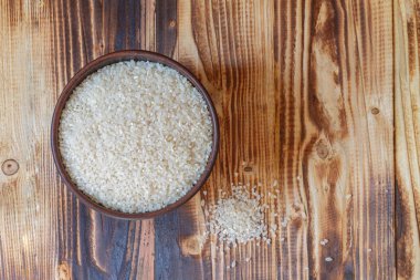 Kahverengi ahşap bir masada yuvarlak pirinçli kahverengi kilden bir kase..