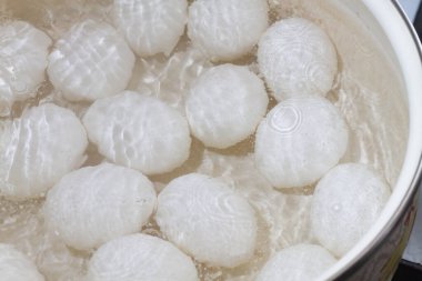 Beyaz tavuk yumurtaları ocaktaki bir tencerede suda kaynatılır..