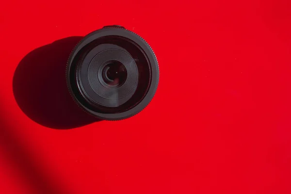 赤い背景にデジタル一眼レフカメラのレンズ — ストック写真