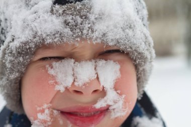 Kışın karda yüzleri olan bir çocuğun portresi..