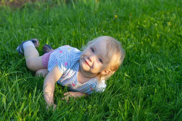 Двухлетняя Девочка Лежит Летом Траве Улыбается — стоковое фото