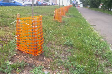 Yol boyunca genç ağaçlar dikilir ve çitlerle çevrili olur..