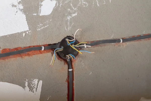 The electrical box with wires is mounted in the wall, the bare wires stick out to the sides.