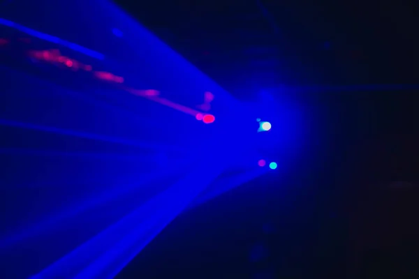 A blurry background of blue laser beams in the dark at a disco.