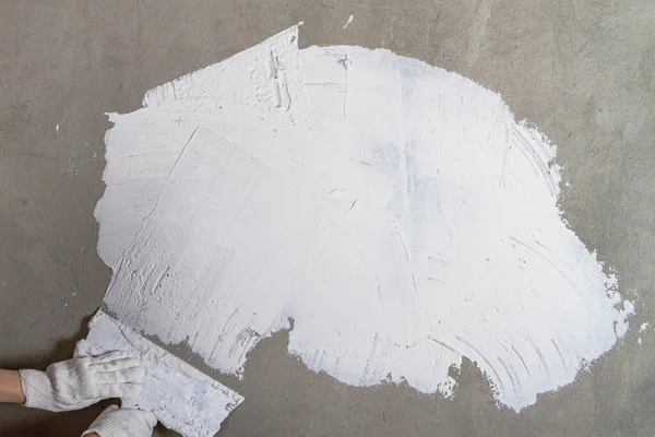 Mit einem Metallspachtel die Wand mit weißem Putzkitt verkleben, bevor Tapeten gestrichen und geklebt werden — Stockfoto