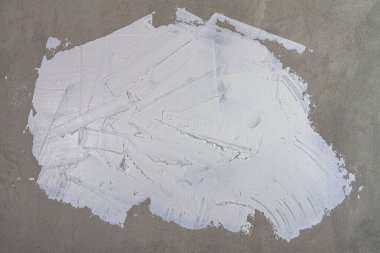 Arka plan beyaz macunla sıvanmış düzensizlikler, lekeler ve alçıda çizikler olan bir duvardan yapılmış..