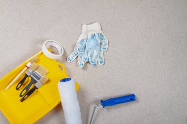 Duvarları boyamak için bir araç. Sarı boya tepsisi, silindir, fırça, eldiven, boya bandı işe gitmeden önce hazırlanır..