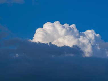 Gri bulutlu mavi gökyüzünde güneş tarafından aydınlatılan büyük bir bulut. Soyut doğal arkaplan.