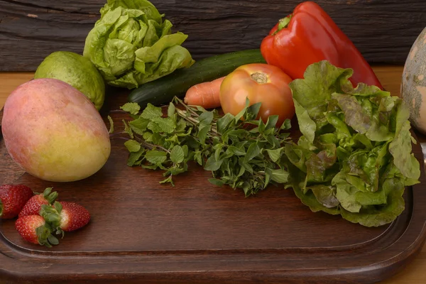 Groenten en fruit op een houten bord — Stockfoto