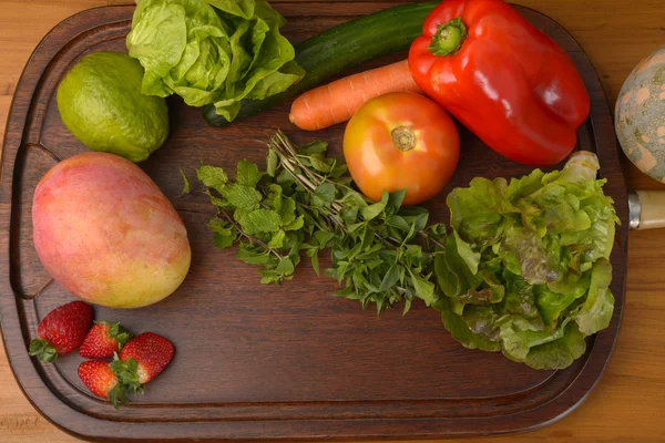 Frutas e legumes em tábua de madeira — Fotografia de Stock