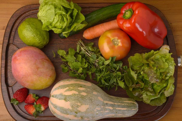 Groenten en fruit op een houten bord — Stockfoto