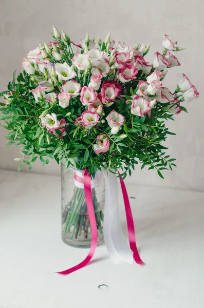 Beautiful romantic bouquet of pink and white eustoma flowers with satin tape in a vase on a white background — Stock Photo, Image