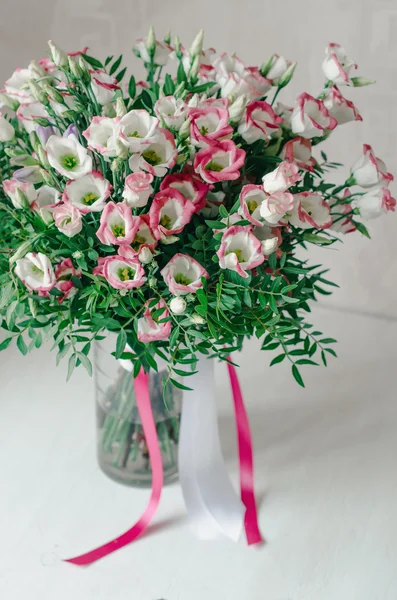 Красивий романтичний букет з рожевих і білих квітів еустоми з атласною стрічкою у вазі на білому тлі — стокове фото