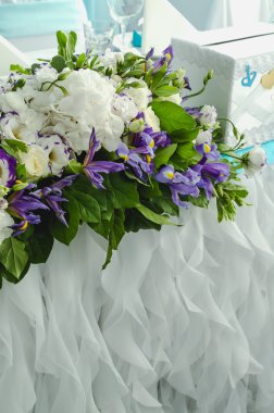 Lüks masa güzel, yemyeşil yaprakları, beyaz ortanca, hassas krem gül, mor eustoma, zengin bezemeli Restoran iris mavi. Stil yaz deniz düğün kavramı. Çiçek aranjmanı.