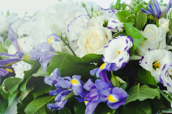 Bunga iris biru yang indah dengan daun yang lebat, hidrangea putih, mawar krim yang lembut. Latar belakang konsep pernikahan musim panas. Susunan bunga, desain. Upacara pengantin wanita dan pengantin pria . Stok Gambar Bebas Royalti