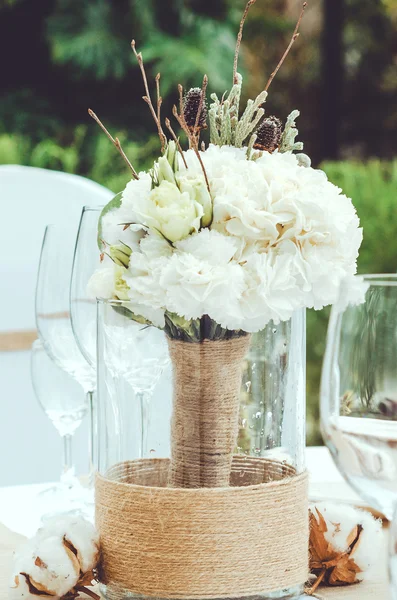 Table set for an event party or wedding reception banquet. Winter bridal bouquet of white carnations, peony, roses flowers with twine in vase on craft background. Elegant wine glass, cutlery, napkin — Stock Photo, Image