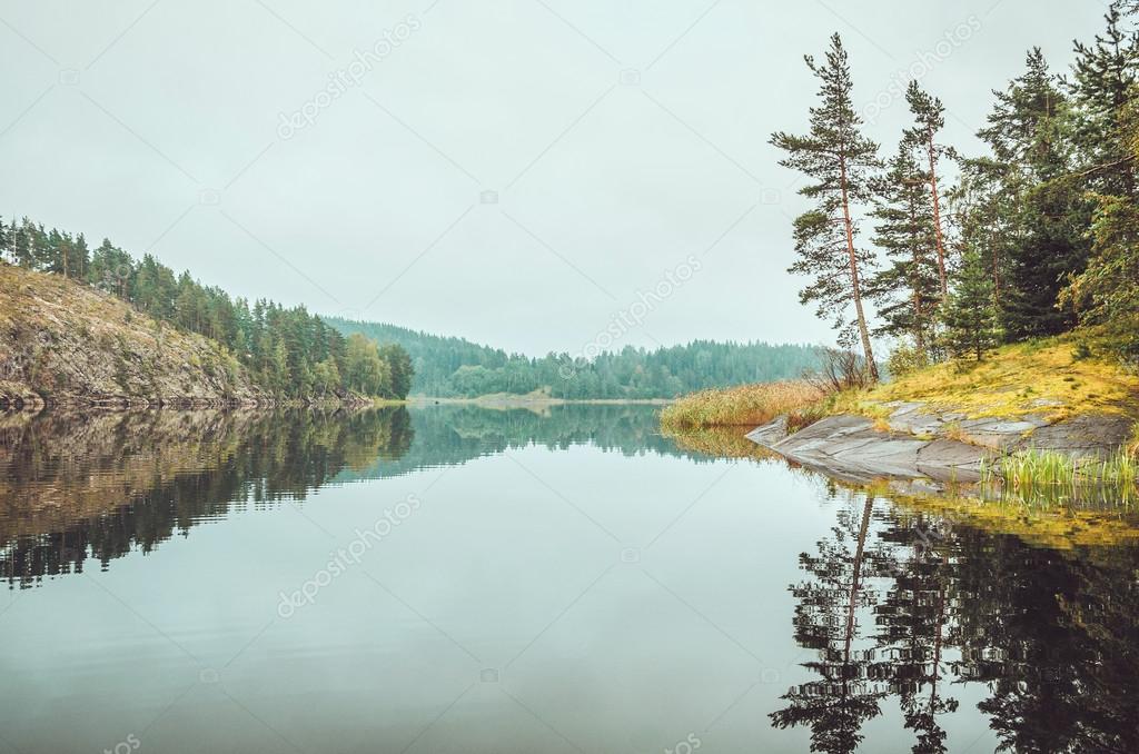 Beautiful autumn landscape with lake, pine trees, natural stone coast in the Republic of Karelia, Ladoga , northern region in Russia. Fall forest, russian tourism and travel concept.