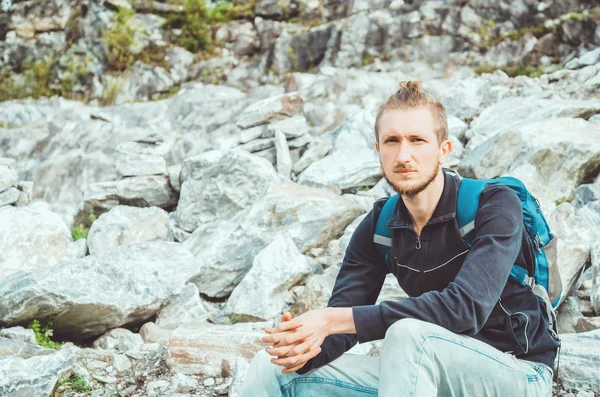 Attractive hiker with backpack on mountain background. Travel, tourism concept, active life. The national Highland Park Ruskeala in the Republic of Karelia, Russia.