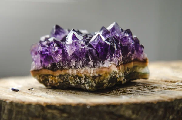 Roccia di ametista grezza con riflessione sull'ametista di cristallo di legno naturale Foto Stock