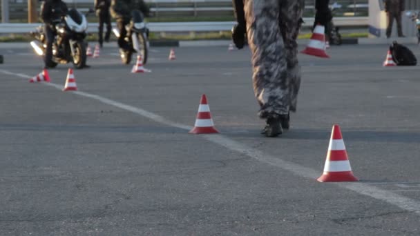 Homem coloca cones de tráfego no chão de treinamento de motocicleta — Vídeo de Stock