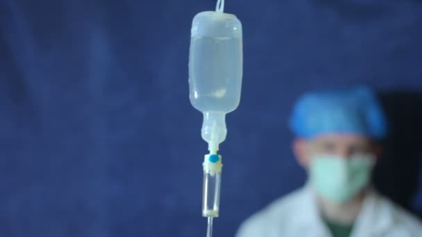 Intraveneus infuus druppelaar tegen de achtergrond van een arts — Stockvideo