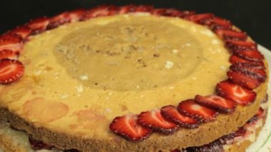 Kız bir kırmızı dilimlenmiş çilek pasta üzerinde saat yönünün tersine döndürme koyar