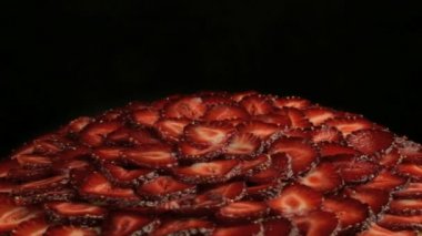 Çok lezzetli kırmızı çilek pasta parçalar üzerinde yavaş yavaş siyah bir arka plan üzerinde saat yönünün tersine döndürür