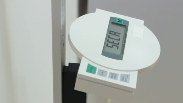 Woman activate electronic scales and measures weight, close-up numeral — Stock Video